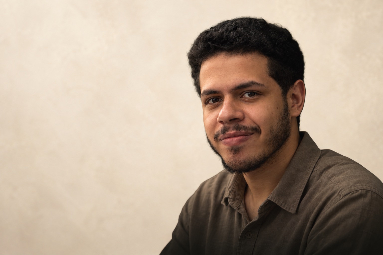 Youssef standing beside a desk in a burgundy shirt